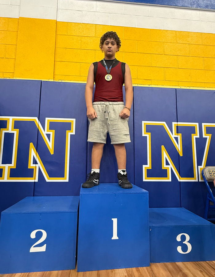 Isaiah standing on the first-place podium after a wrestling competition